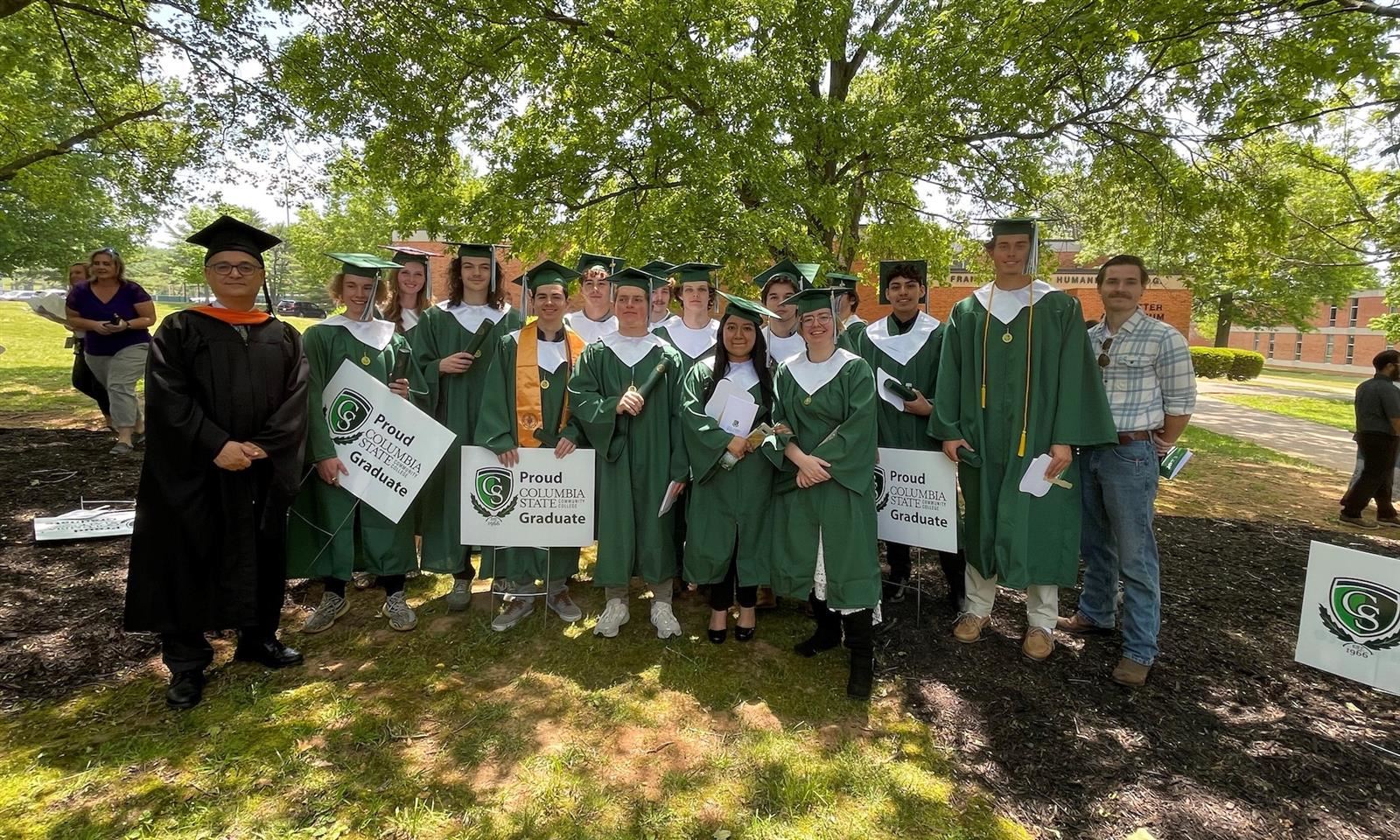 Students in graduation robes smile